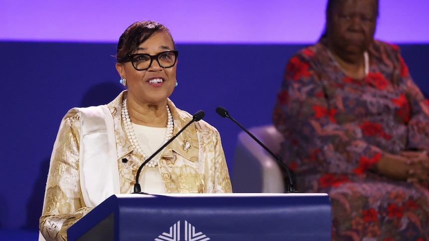 A woman smiles while speaking at a lectern