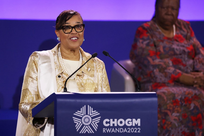 A woman smiles while speaking at a lectern