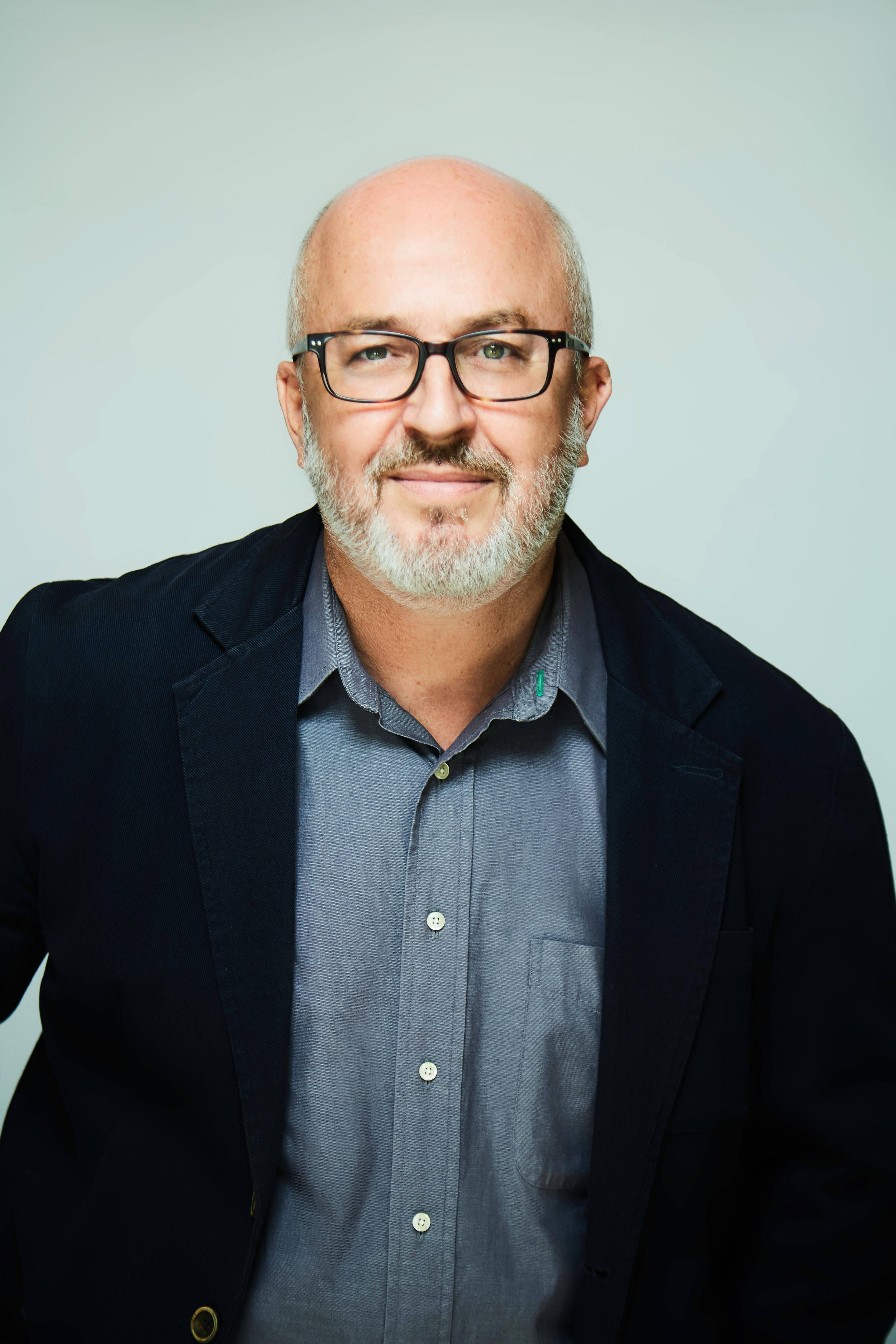 Hombre con vello facial gris y cabeza calva con traje y gafas oscuras