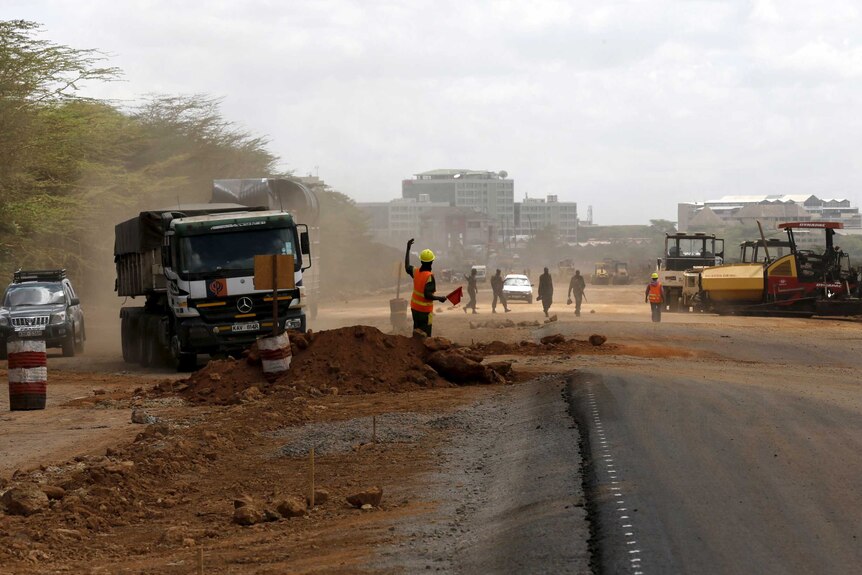 Constructions workers on dirt and tar road