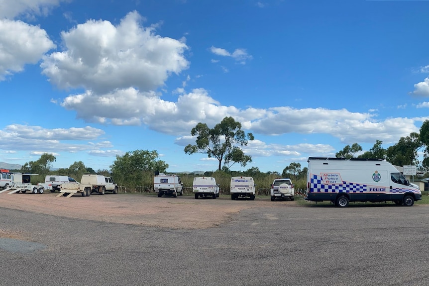 Eight police and SES vehicles parked at a rest stop on the side of a road 