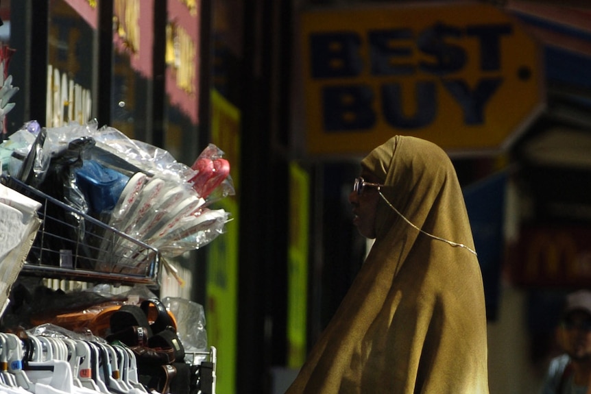 A woman in a headscarf browsing at the shops on Sydney Road in Melbourne.