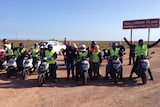 Senior citizens on their scooters besides a Nullarbor Plain sign, Sept 2014