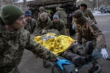 Ukrainian military medics carry an injured Ukrainian serviceman evacuated from the battlefield.