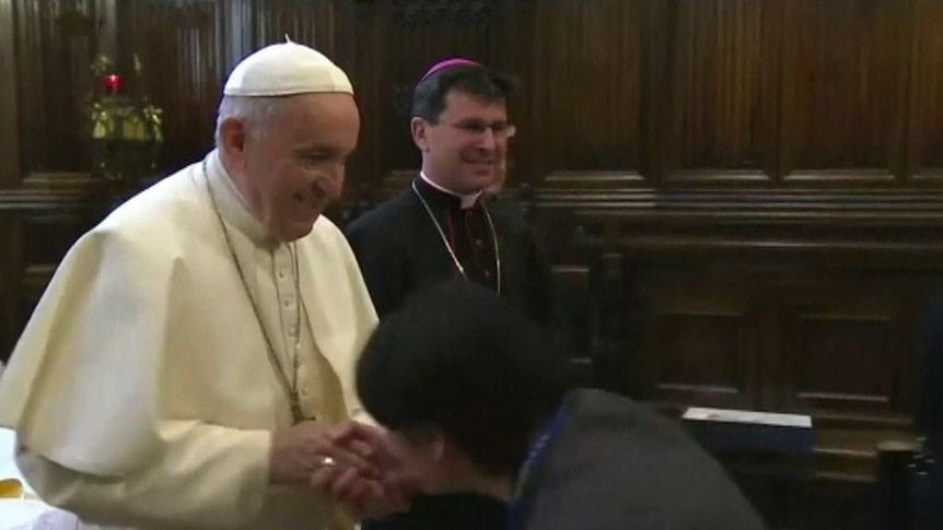 The Pope withdraws his hand as a worshipper attempts to kiss his ring.