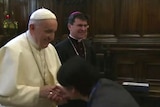 The Pope withdraws his hand as a worshipper attempts to kiss his ring.