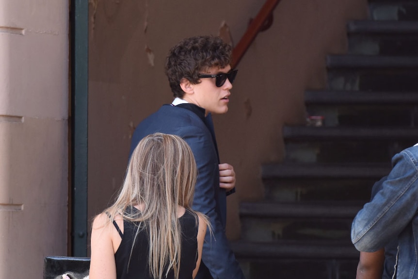 Side of photo of Zane Alchin wearing sunglasses as he walks into a building.