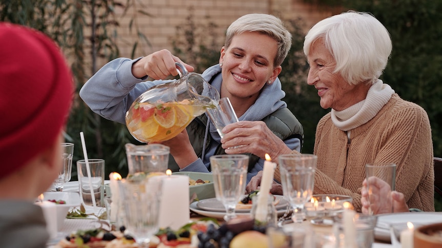 A younger woman with an elderly woman having a party at a happy family gathering in a backyard.
