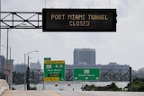 Signs warning of road closures are seen above the road in Miami Beach.