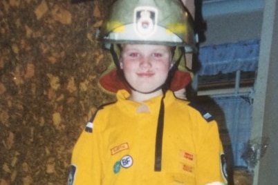 A young child in a firefighting uniform.