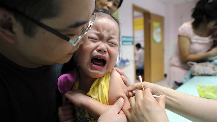 A child cries while receiving a shot in a health station.