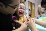 A child cries while receiving a shot in a health station.