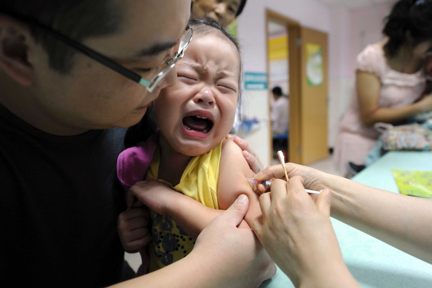 A child cries while receiving a shot in a health station.