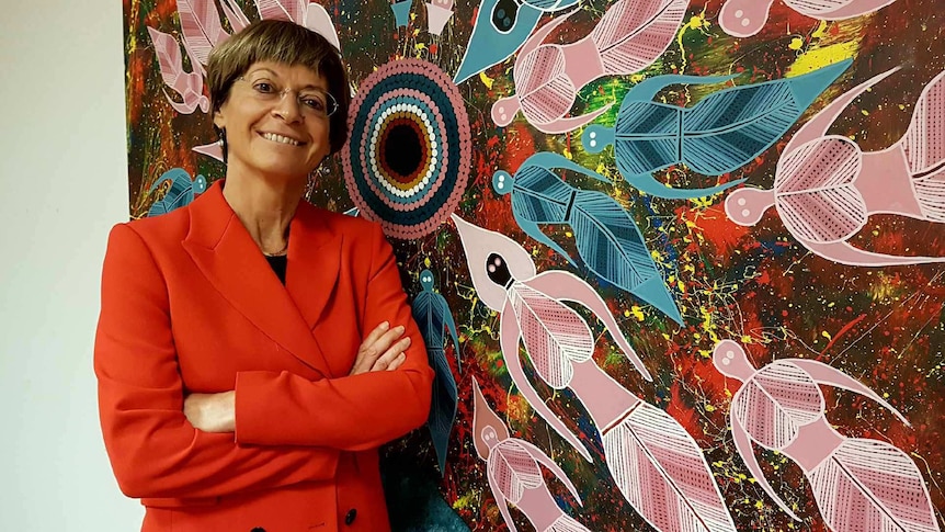 Deborah Glass poses next to a painting from The Torch in her office.