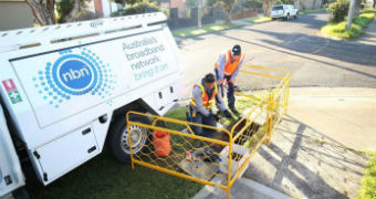 Workmen install broadband infrastructure under a residential pavement.