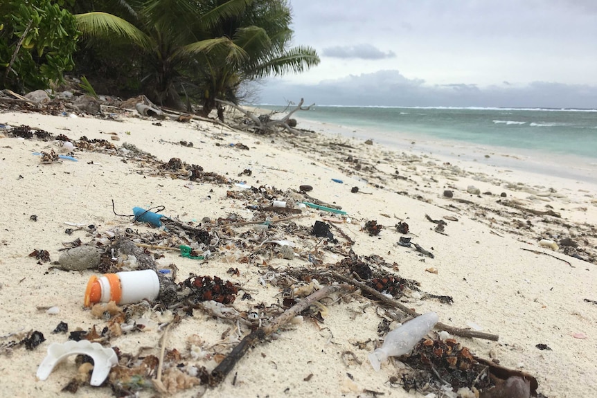 Plastic debris on a beach with palm trees and green ocean on the Cocos (Keeling) Islands in north-west Australia.