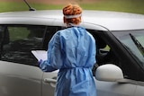 Health worker in PPE at car window at a COVID-19 testing hub at Lawnton, north of Brisbane.