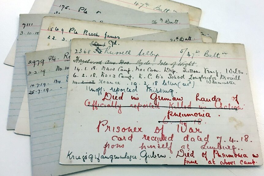 A collection of small index cards with handwritten cursive script. On the top card the words 'prisoner of war' are prominent