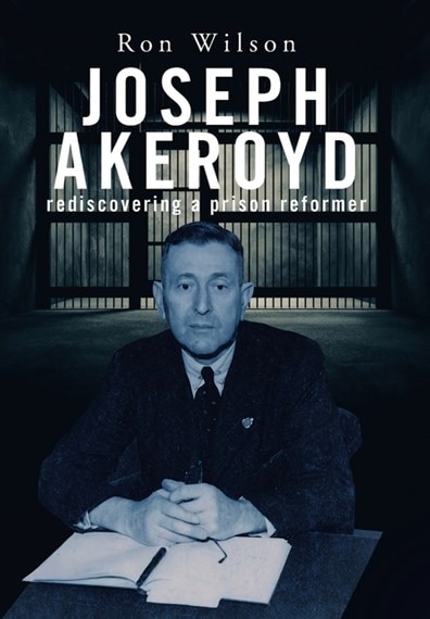 Cover of a book, dark background, man sitting at desk