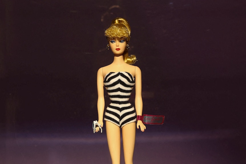 A Barbie with a ponytail wearing a black and white swimsuit 