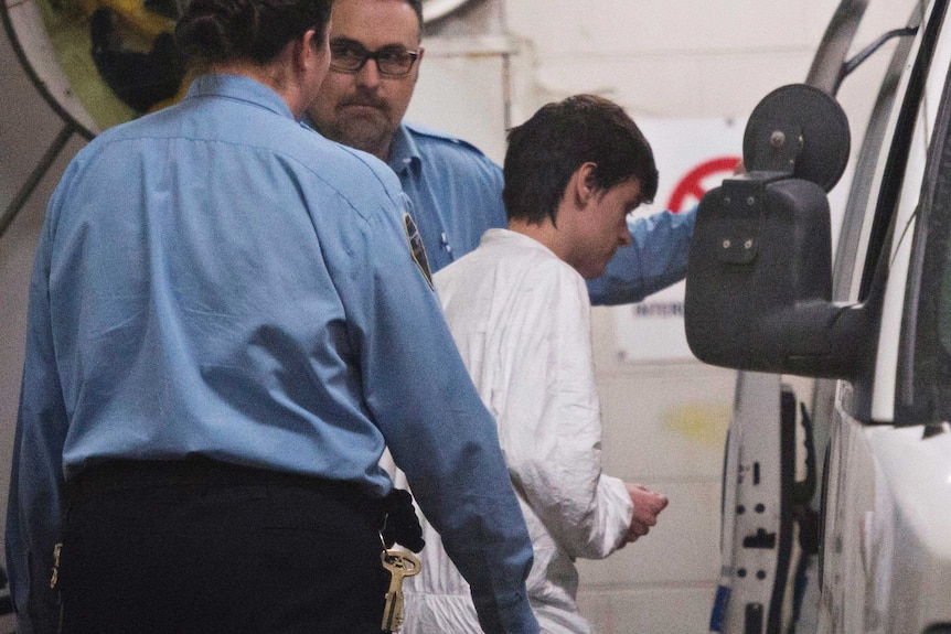 Alexandre Bissonnette is handcuffed and escorted to a van wearing a white jumpsuit after appearing in court