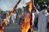Pakistani Muslim demonstrators burn a US flag as they attempt to reach the US embassy in Islamabad.