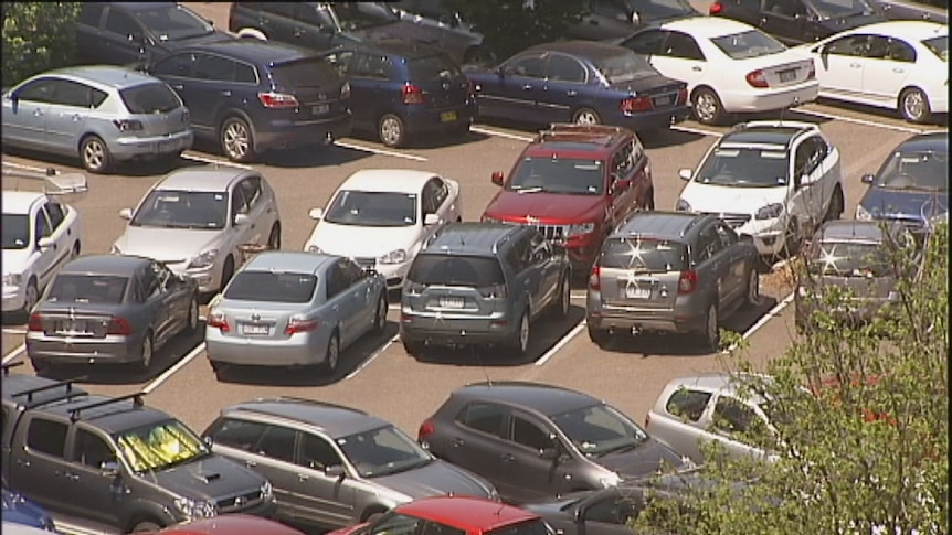 Video still: Close up of vehicles tightly packed in Woden car park.