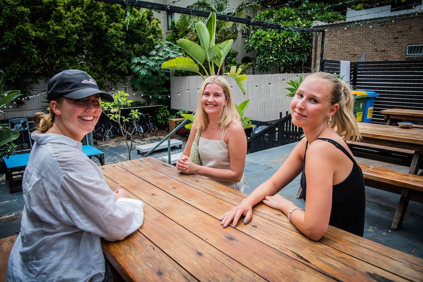 Three young women sitting on a bench.