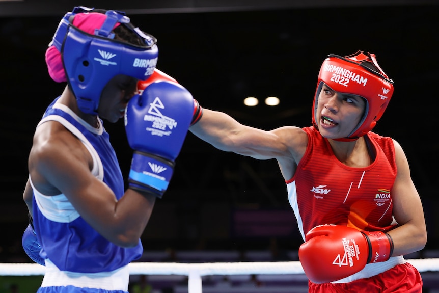 A female boxer extends her right arm to punch her opponent on the side of the head during a bout..