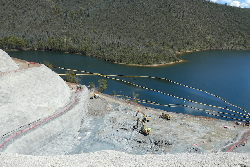 An aerial shot of construction work on the shores of a dam.