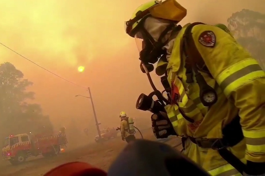 a person  in protective gear with a mask sating in the middle of smoke