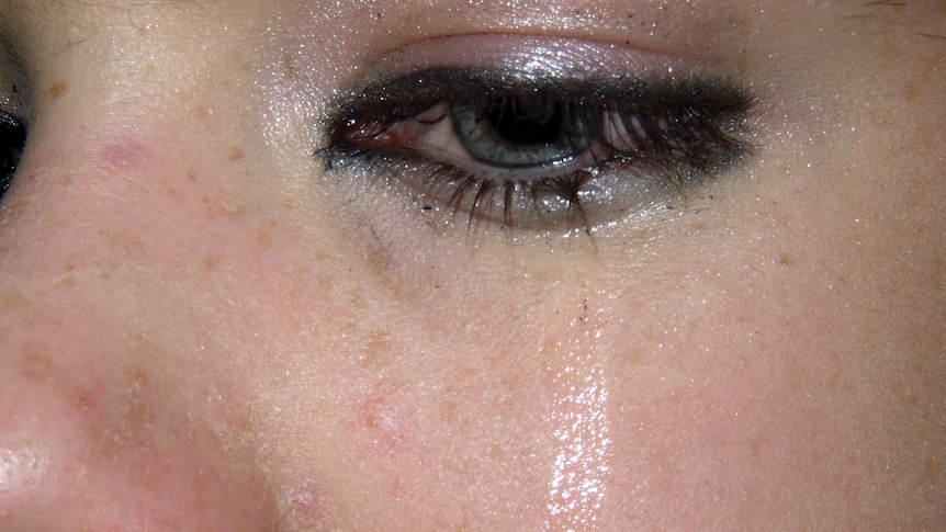 A tear runs down a girls cheek as she cries.