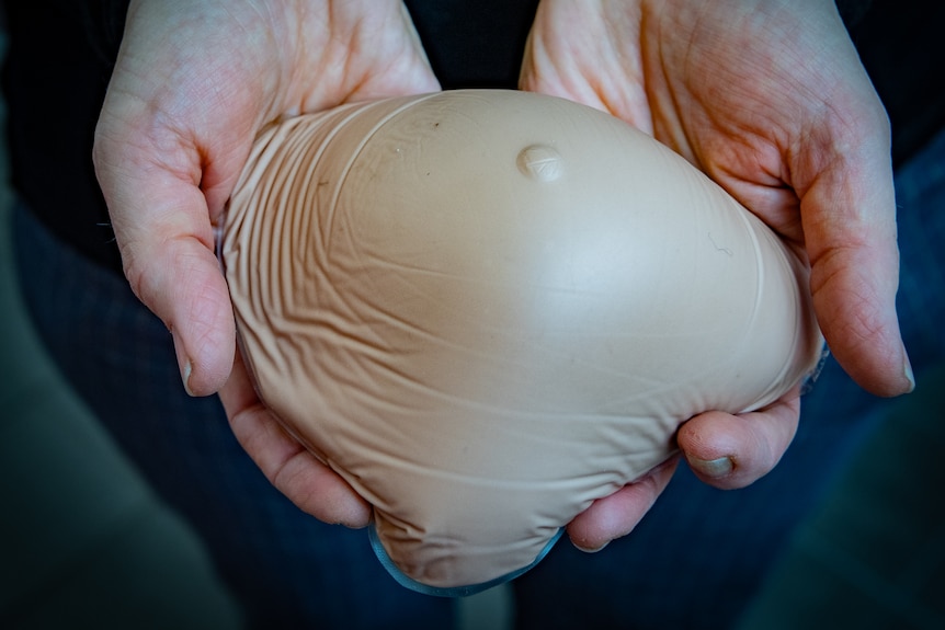A close up of Rebecca Smyth's hands show them holding her prosthetic breast.