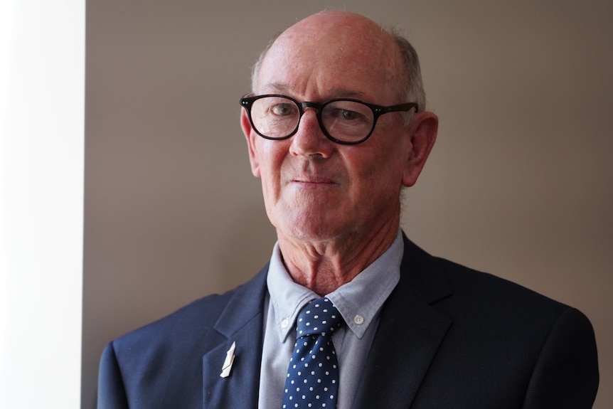 A man wearing glasses and a suit and tie.