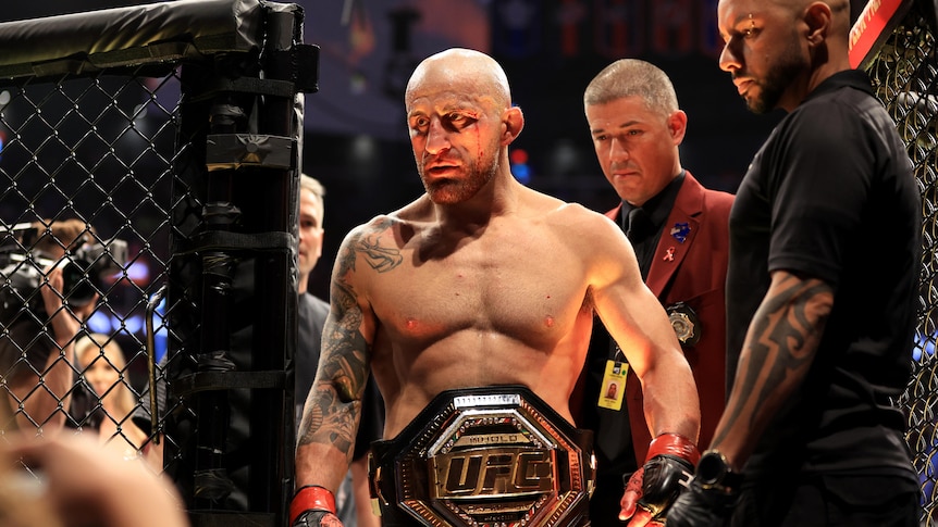 A man celebrates with his championship belt after winning a title fight 