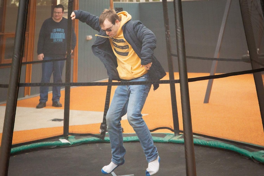 A teenager with Down's syndrome is jumping on a trampoline.