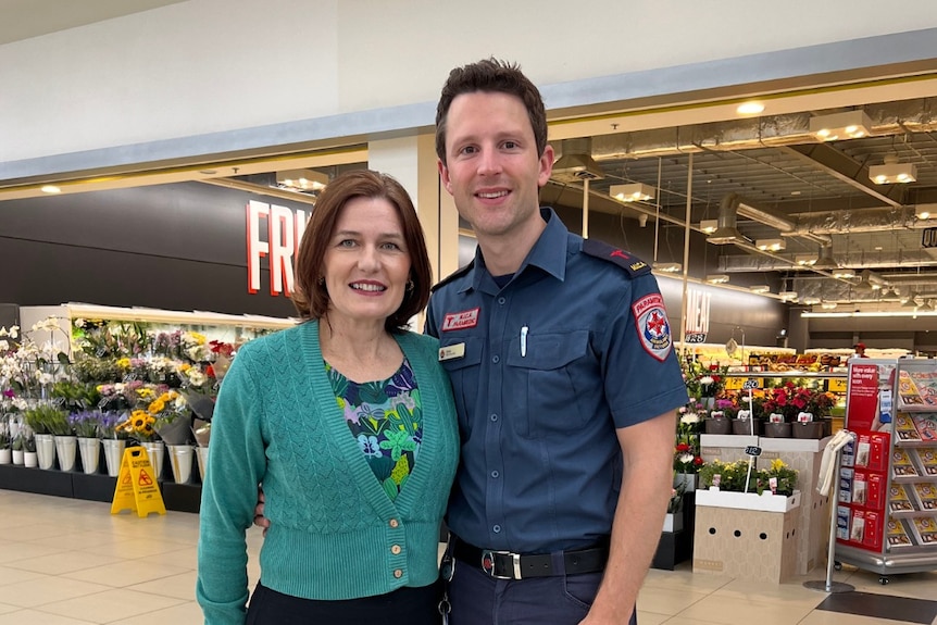 A woman with a green jumper standing next to a man wearing a paramedics uniform outside a supermarket
