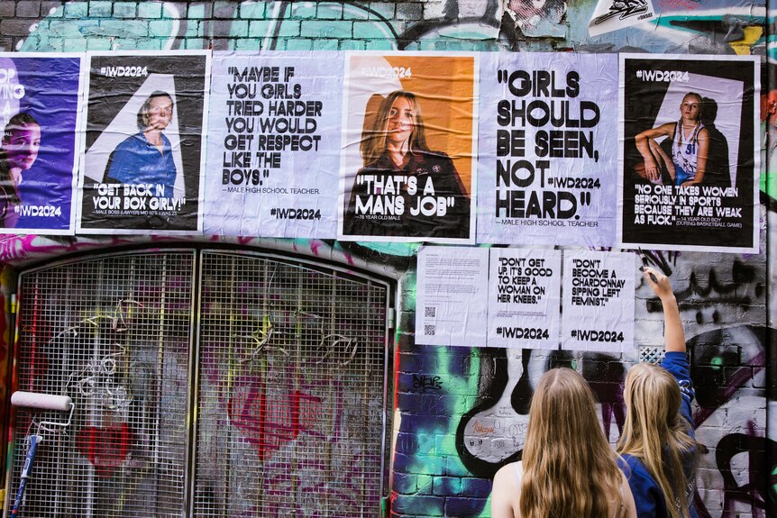 a selection of posters, one reading "girls should be seen not heard" glued to Hosier Lane's graffitied walls. 