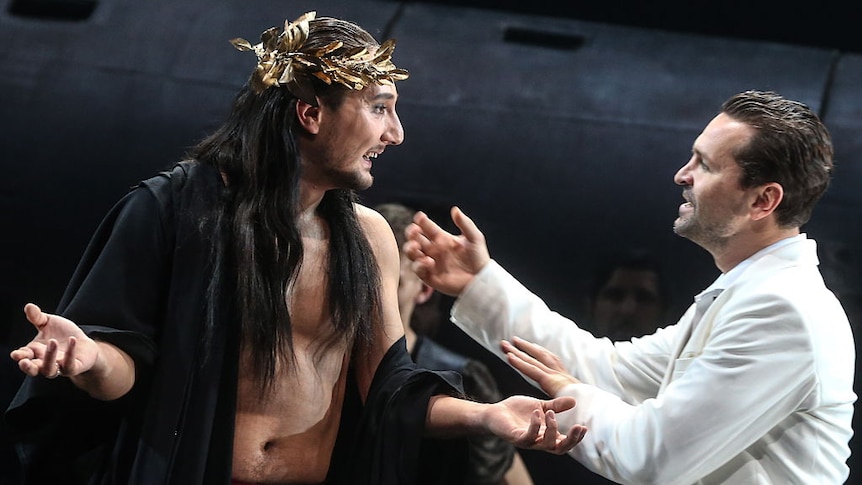 Two male actors on stage - one wearing a gold crown of laurel leaves