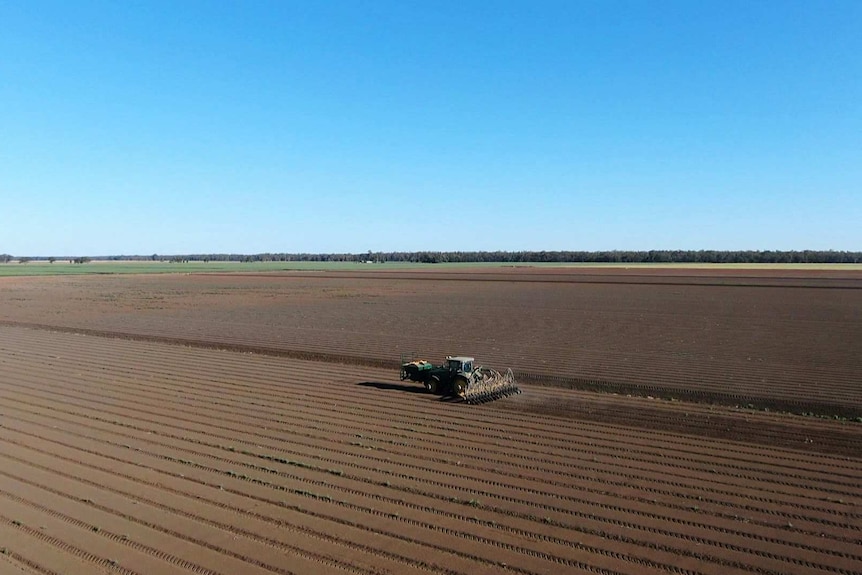 A tractor in a large brown field.