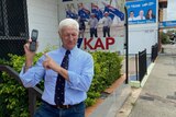 Bob Katter holding up a Nokia phone outside his office. 