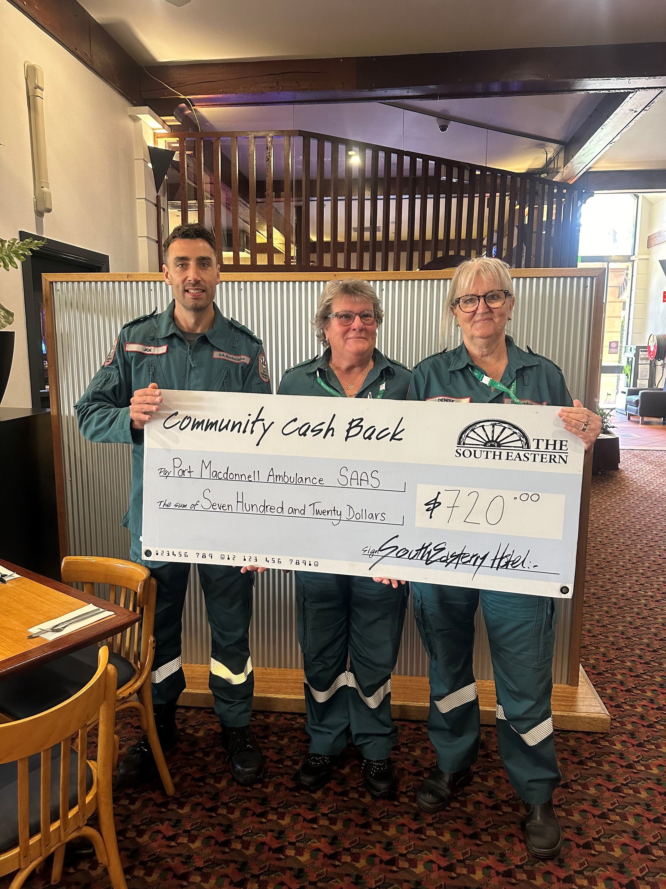 Three ambulance workers hold a giant cheque