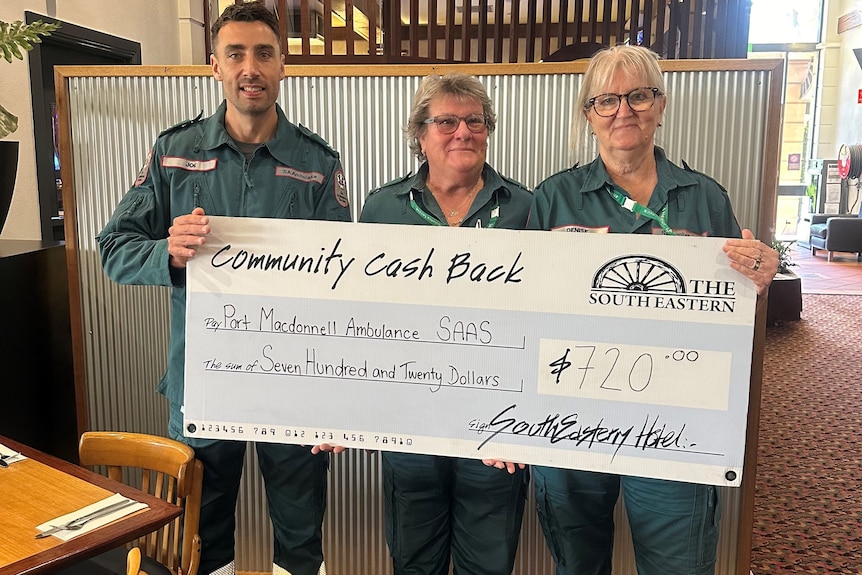 Three ambulance workers hold a giant cheque