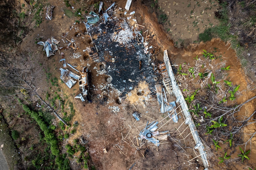 An aerial shot shows the burnt out foundations of a dwelling.  