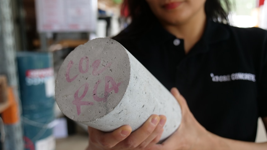 A woman holds a concrete cylinder in her hands