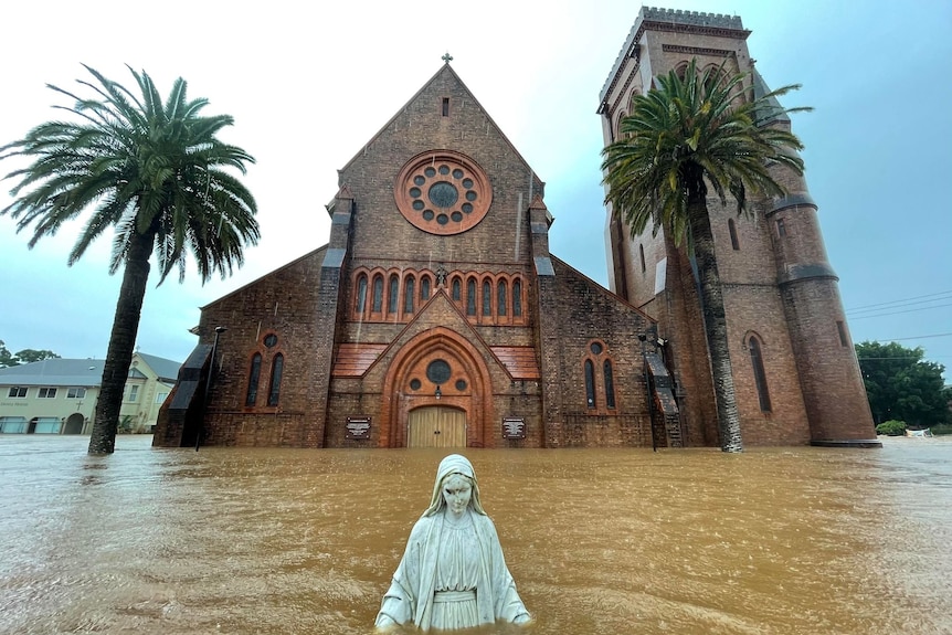 A statue inundated by floodwater outside a cathedral.