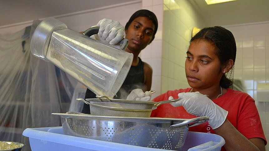 Two girls processing the powder from boab flesh