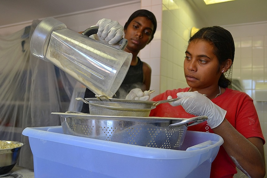 Two girls processing the powder from boab flesh