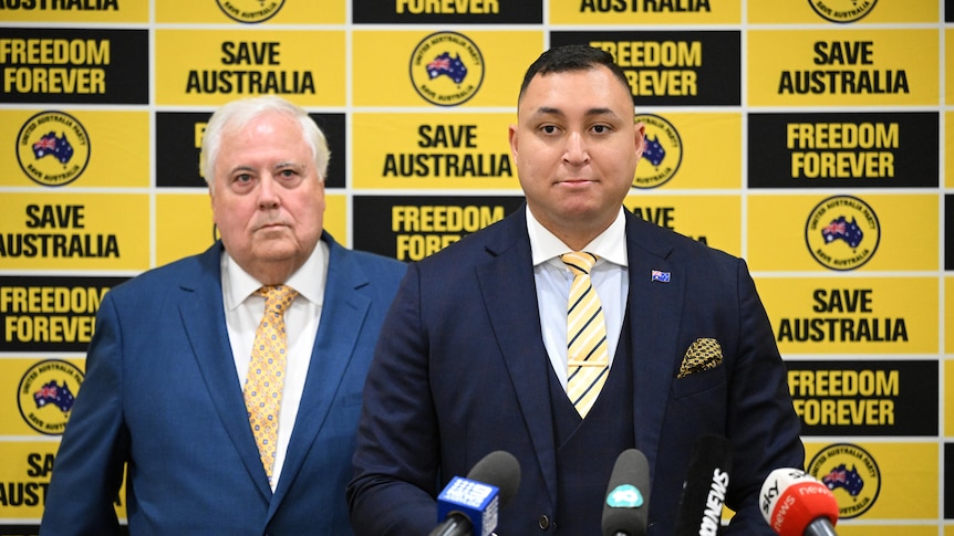 Two men in a suit at a press conference 