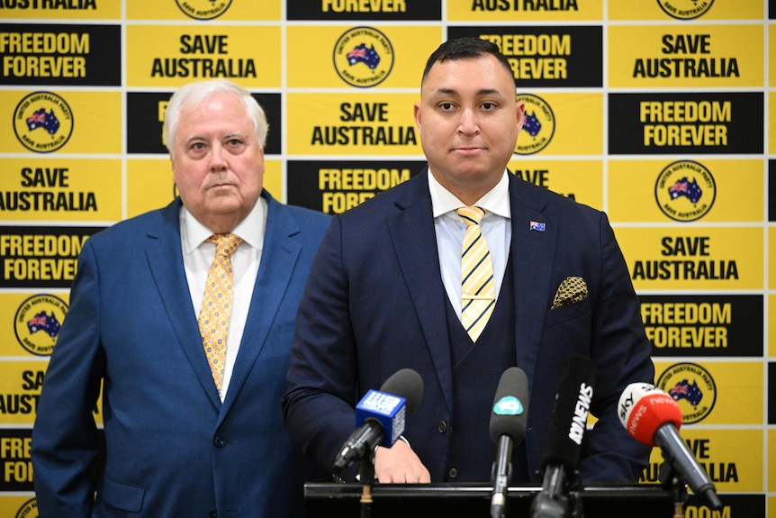 Two men in a suit at a press conference 